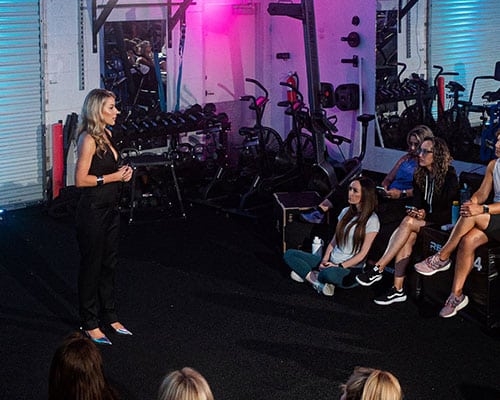 Image of emily in neon room with people listening to her talk